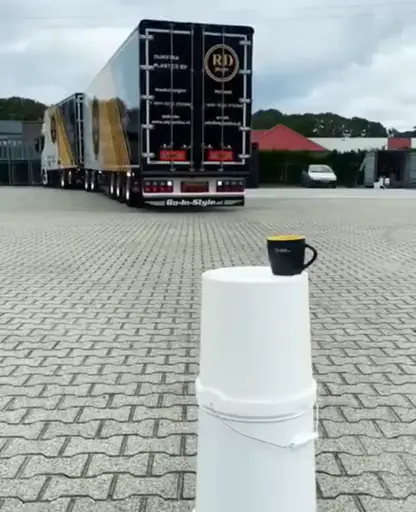 A truck is reversing precisely and lowers a tea bag into a cup.